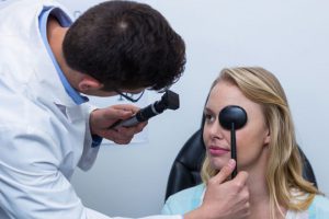 Male doctor giving female patient an eye exam